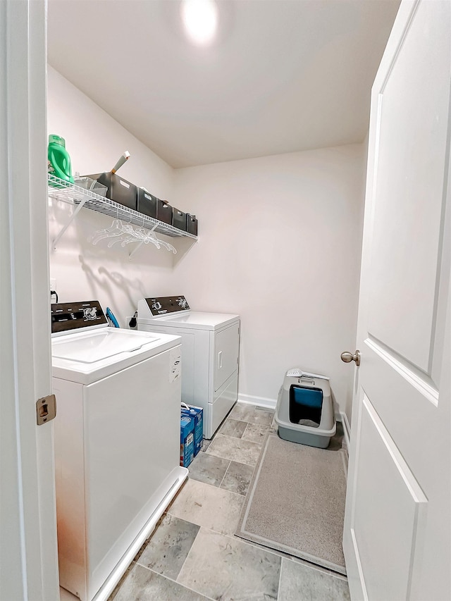 laundry area with separate washer and dryer, laundry area, baseboards, and stone finish floor