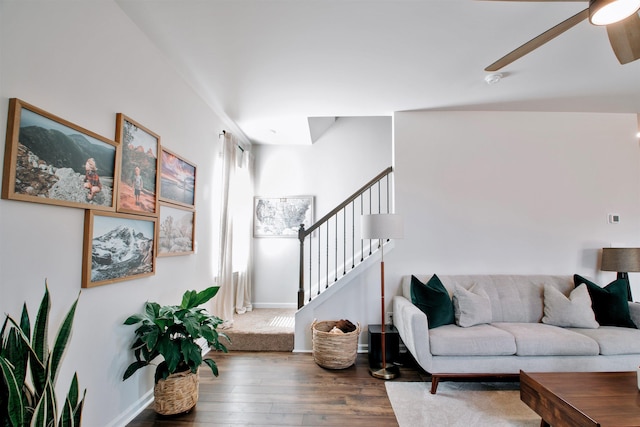 living area featuring stairway, ceiling fan, baseboards, and wood finished floors
