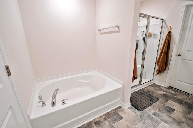 full bath featuring a stall shower, baseboards, stone finish flooring, and a bath