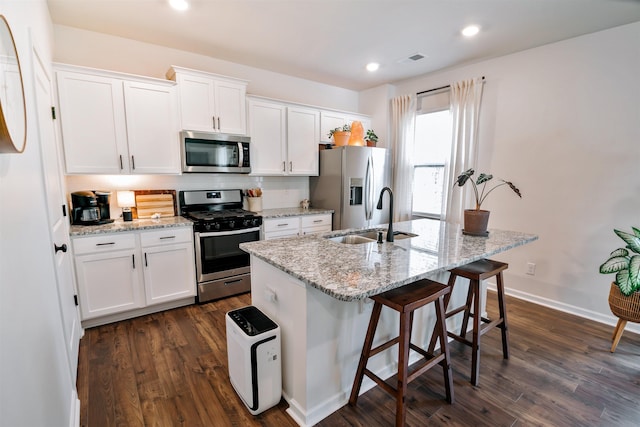 kitchen featuring an island with sink, a sink, white cabinets, visible vents, and appliances with stainless steel finishes