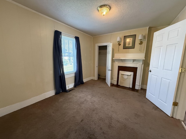 unfurnished living room with crown molding, a textured ceiling, carpet, and baseboards