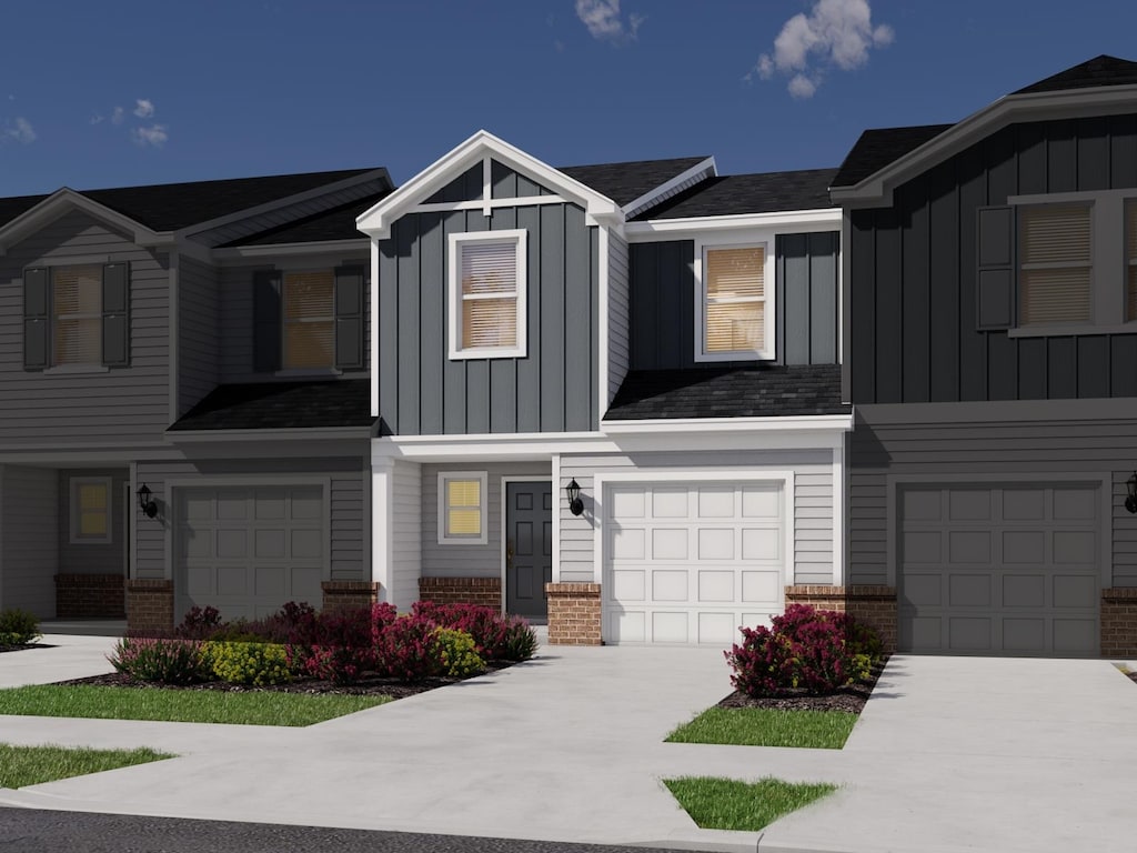 view of front of house with driveway, an attached garage, brick siding, and board and batten siding