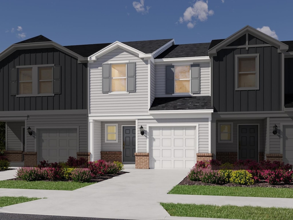 view of front facade featuring an attached garage, board and batten siding, brick siding, and driveway