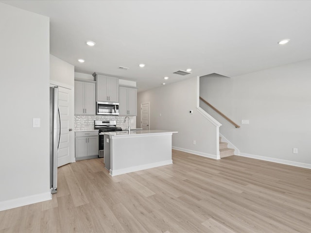 114 Arrow, Greer, SC 29651 - kitchen with stainless steel appliances, gray cabinetry, light wood-style flooring, a sink, and tasteful backsplash