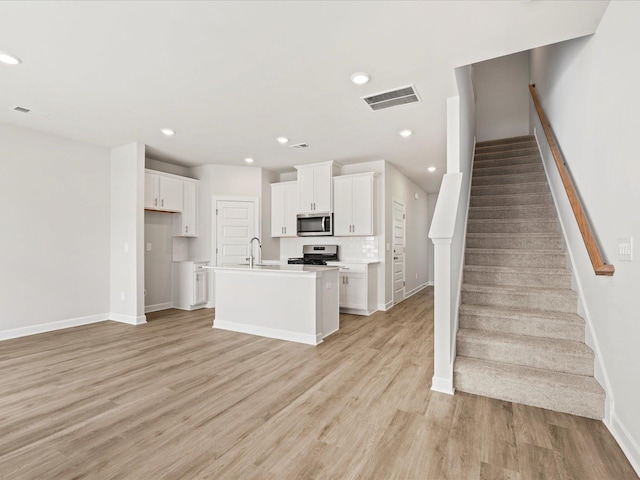122 Arrow, Greer, SC 29651 - kitchen featuring appliances with stainless steel finishes, light wood finished floors, white cabinetry, a center island with sink, and light countertops
