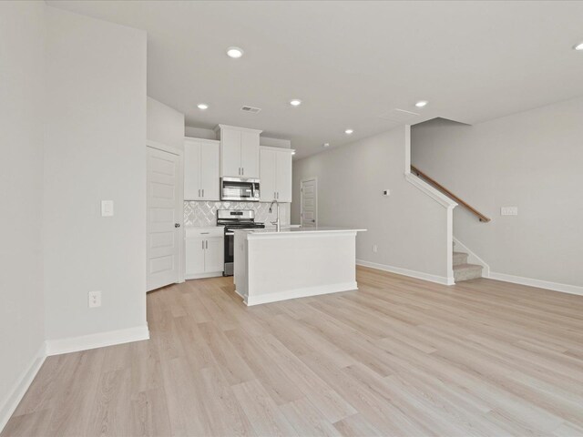124 Arrow, Greer, SC 29651 - kitchen featuring stainless steel appliances, light wood finished floors, backsplash, white cabinets, and open floor plan