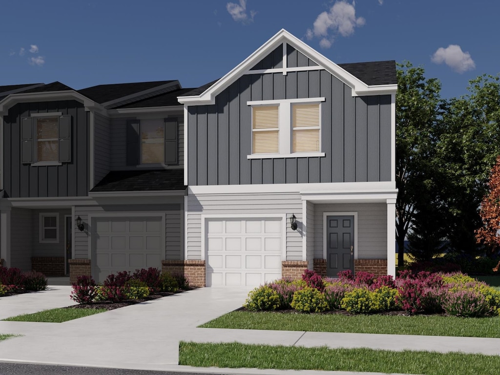 view of front of home featuring driveway, an attached garage, brick siding, and board and batten siding