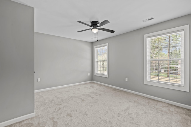unfurnished room featuring a healthy amount of sunlight, baseboards, a ceiling fan, and visible vents