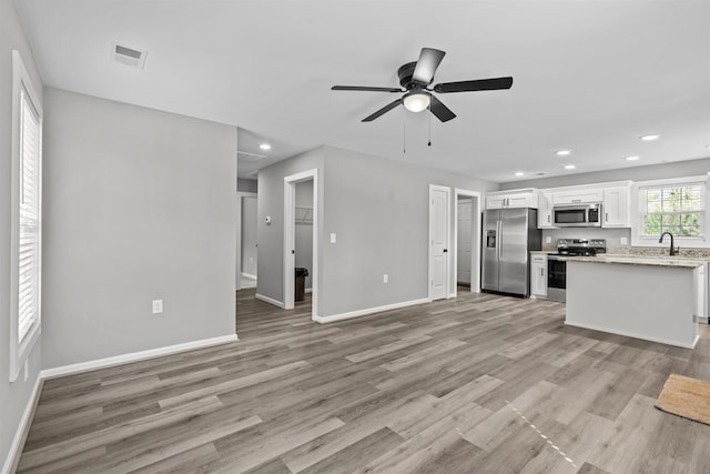 interior space with recessed lighting, baseboards, ceiling fan, visible vents, and a sink