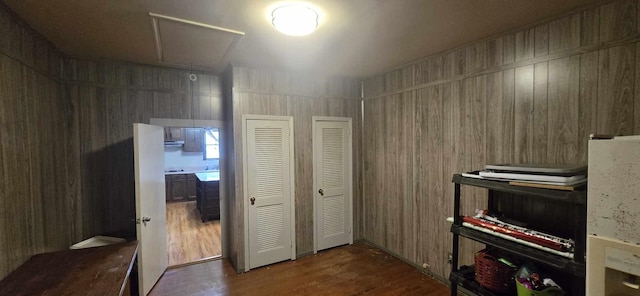 misc room featuring attic access, wooden walls, and wood finished floors