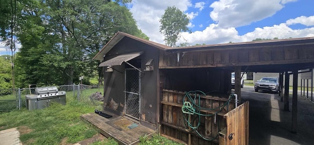 view of outdoor structure featuring fence and an attached carport