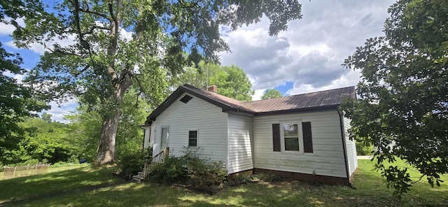 view of side of property featuring metal roof, a chimney, and a lawn
