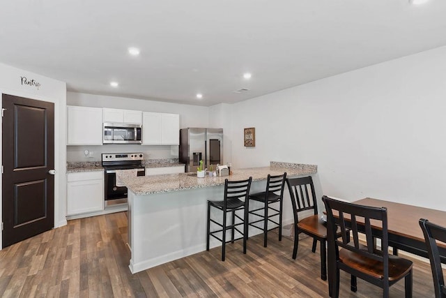 kitchen with light stone countertops, recessed lighting, white cabinetry, a peninsula, and appliances with stainless steel finishes