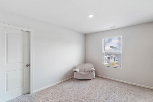 living area with baseboards, visible vents, and carpet