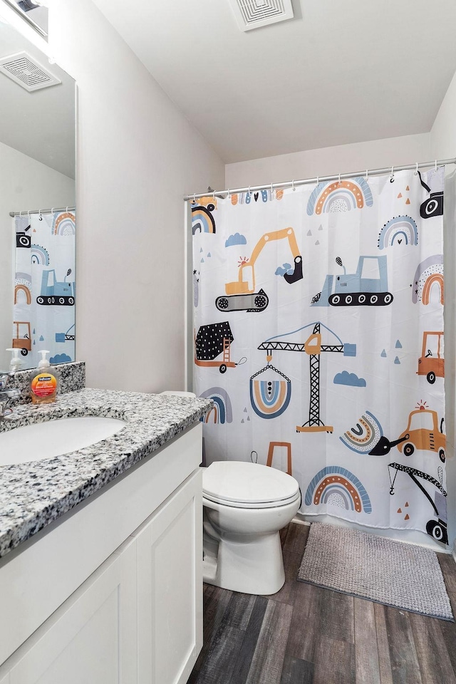 full bath with toilet, vanity, visible vents, and wood finished floors