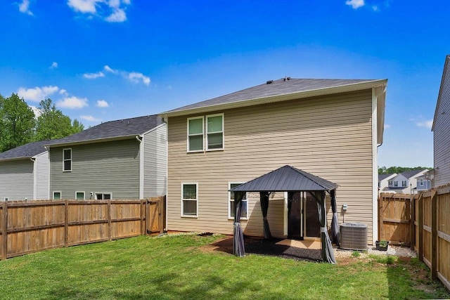 rear view of house with a fenced backyard, a gazebo, cooling unit, and a lawn