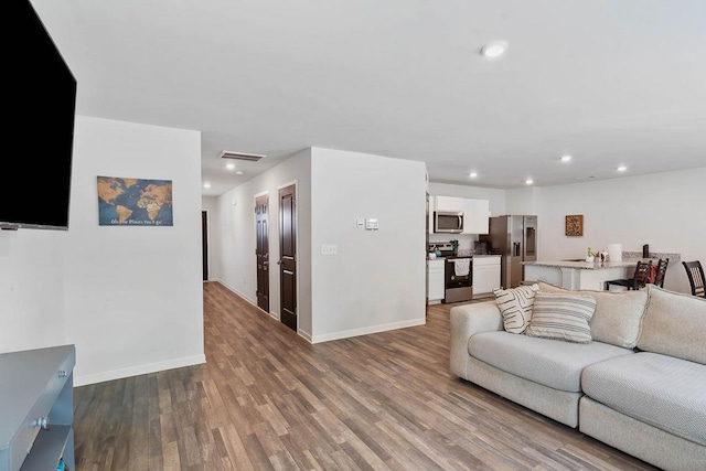 living room with wood finished floors, baseboards, and recessed lighting