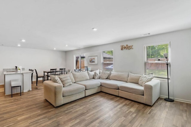 living area featuring recessed lighting, a wealth of natural light, visible vents, and light wood-style floors