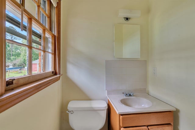 bathroom featuring vanity, toilet, and decorative backsplash