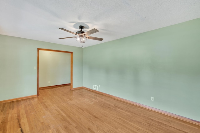 empty room with a ceiling fan, baseboards, light wood-type flooring, and visible vents
