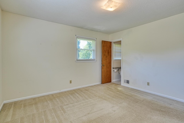 spare room with light colored carpet, baseboards, and visible vents