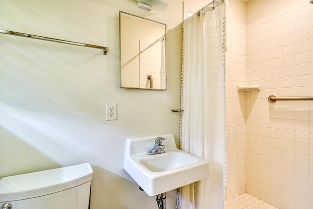 bathroom with a stall shower, toilet, and a sink