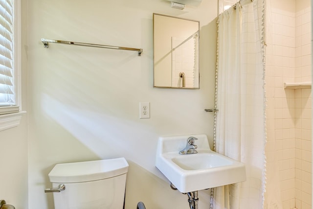 bathroom featuring toilet, a shower with curtain, and a sink