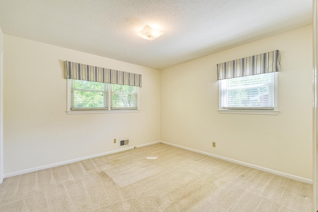spare room with baseboards, a textured ceiling, visible vents, and carpet floors