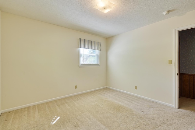 spare room featuring a textured ceiling, baseboards, and carpet floors