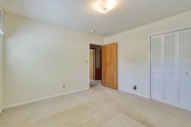 unfurnished bedroom with light carpet, a closet, and baseboards