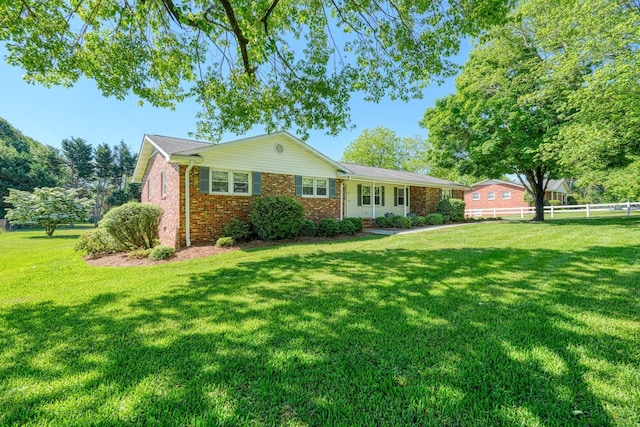 view of front of property featuring a front lawn, brick siding, and fence