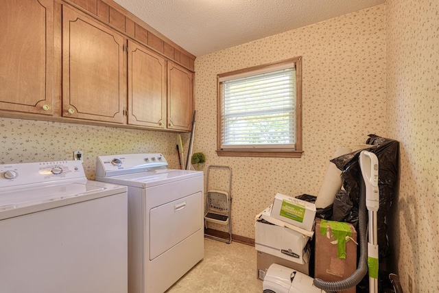 laundry area with cabinet space, wallpapered walls, washer and clothes dryer, and a textured ceiling