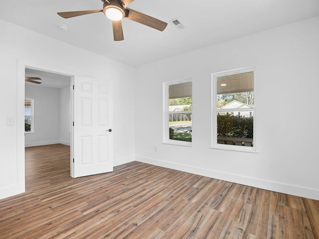 unfurnished room with light wood-type flooring, ceiling fan, baseboards, and visible vents