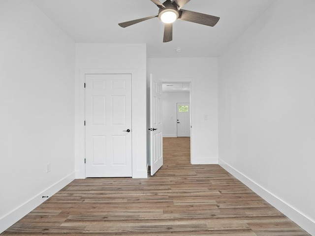 unfurnished bedroom with ceiling fan, baseboards, and light wood-type flooring
