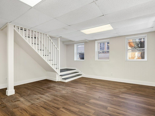 below grade area featuring baseboards, stairs, plenty of natural light, and wood finished floors