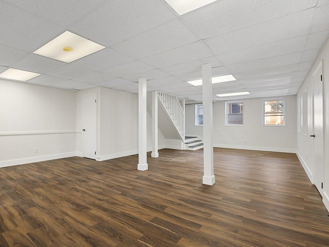 basement featuring stairway, dark wood-type flooring, and a paneled ceiling