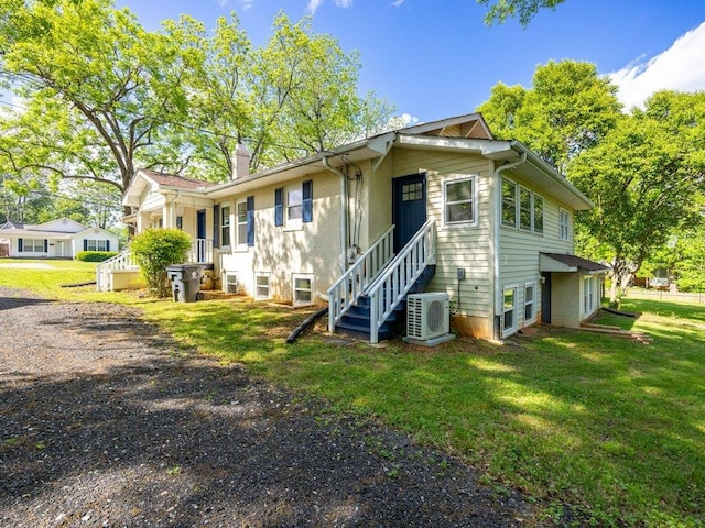 view of front of home with a chimney, a front lawn, and ac unit