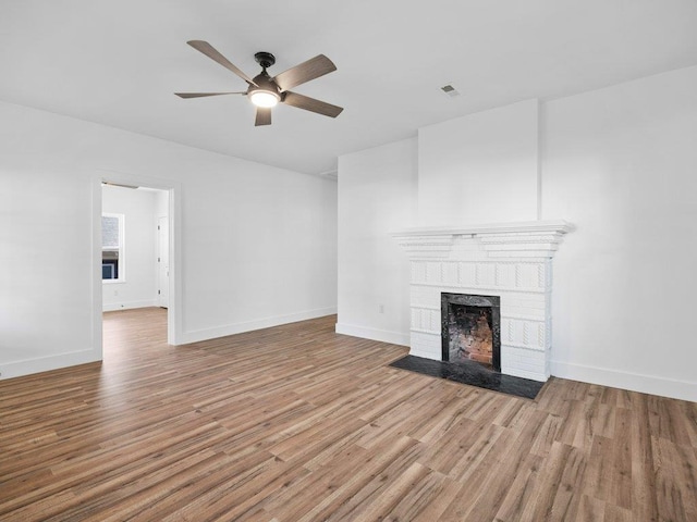 unfurnished living room with a brick fireplace, ceiling fan, and wood finished floors