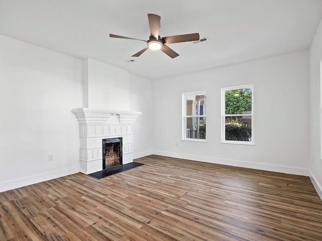 unfurnished living room with a ceiling fan, baseboards, visible vents, wood finished floors, and a fireplace