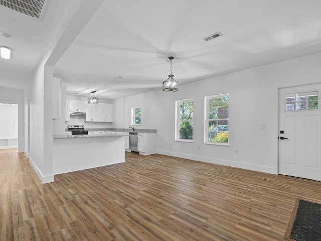 unfurnished living room with baseboards, an inviting chandelier, visible vents, and wood finished floors