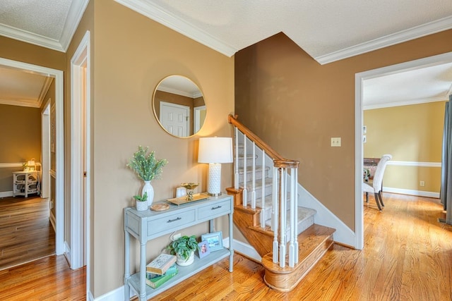 stairs with wood finished floors, crown molding, and baseboards