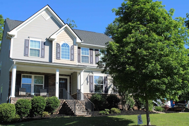 view of front of house with a porch, a front yard, and stairway