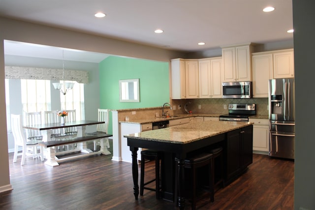 kitchen with appliances with stainless steel finishes, decorative backsplash, a chandelier, a sink, and light stone counters