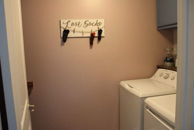 clothes washing area featuring washing machine and clothes dryer and cabinet space