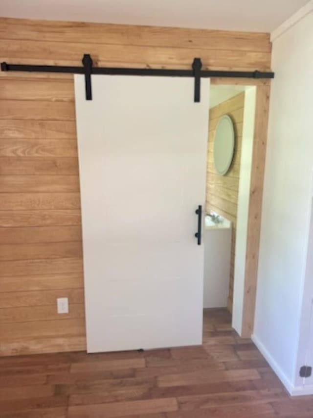 detailed view of a barn door, wood finished floors, and wood walls