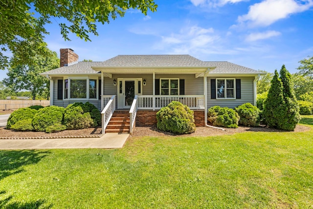 view of front of property with a chimney, a porch, a front yard, and a shingled roof