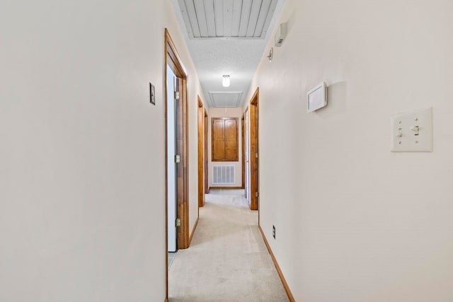hallway with attic access and light colored carpet