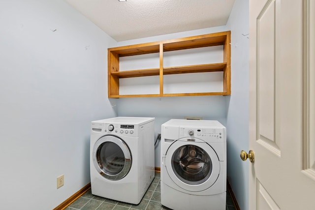 clothes washing area featuring washing machine and clothes dryer, baseboards, a textured ceiling, and dark tile patterned floors