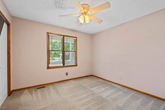 unfurnished bedroom featuring light colored carpet, baseboards, a textured ceiling, and ceiling fan