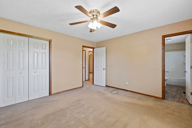 unfurnished bedroom with light carpet, baseboards, a closet, ensuite bath, and a ceiling fan
